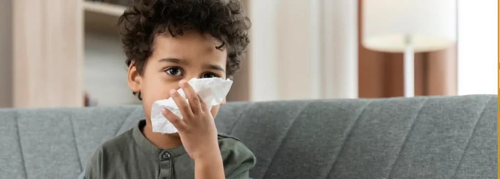 Criança com lenço de papel no rosto demonstra preocupação, relacionado ao aumento de casos respiratórios após o retorno às aulas.