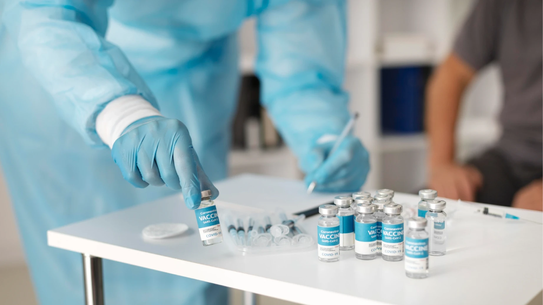 Profissional de saúde manipulando doses de uma vacina 100% brasileira contra a Covid-19 em fase final de testes, com múltiplas amostras na bancada.