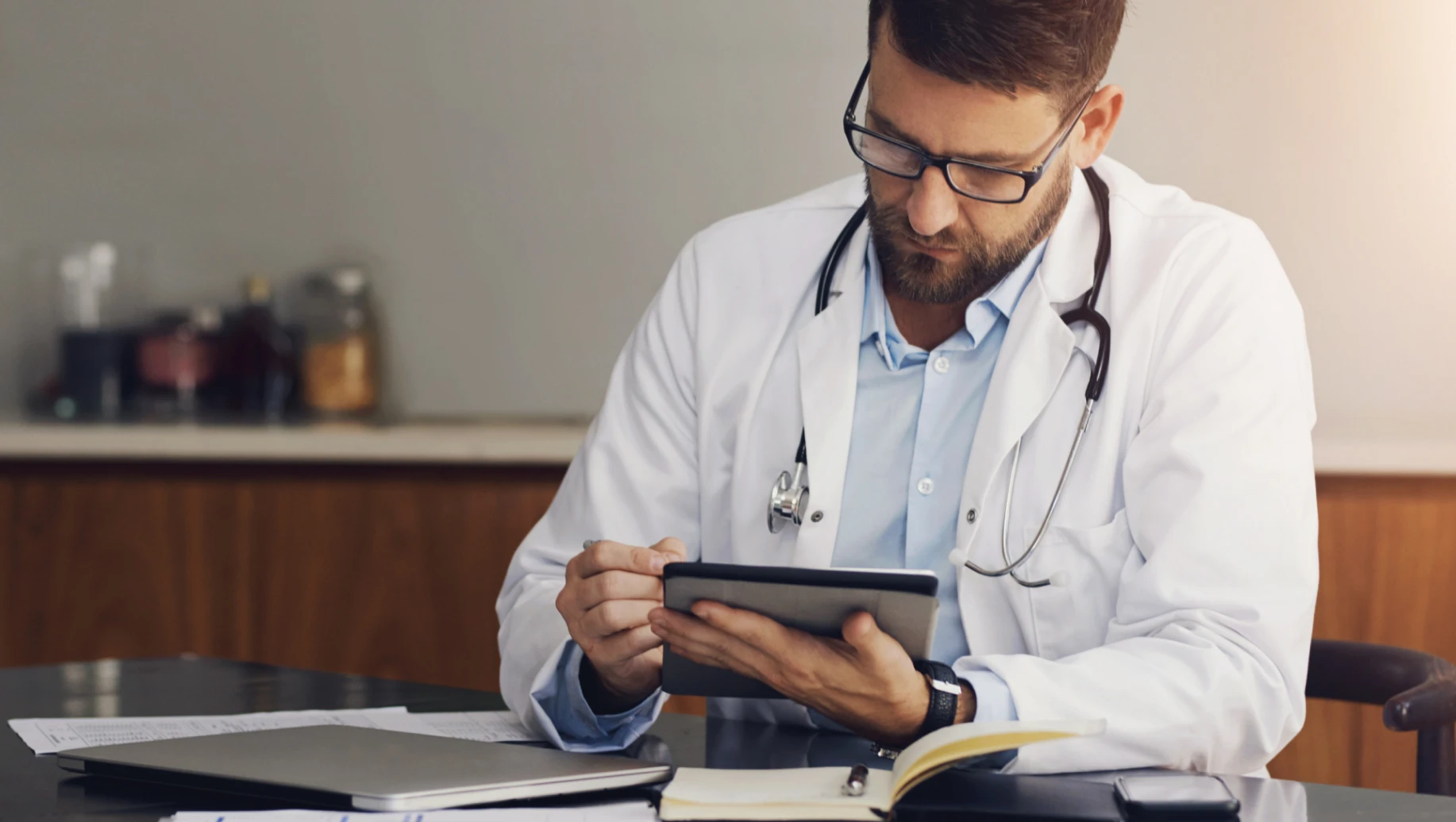 Médico revisando informações em tablet, reforçando a importância da atualização das regras da auditoria médica pelo CFM para maior segurança de médicos e pacientes.