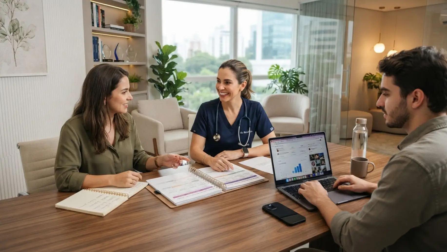 Regras para Médicos no Instagram: Reunião em consultório com médicos e pacientes: profissional de saúde sentada à mesa, conversando com duas pessoas enquanto analisa documentos e dados em um notebook, com janelas e plantas ao fundo.