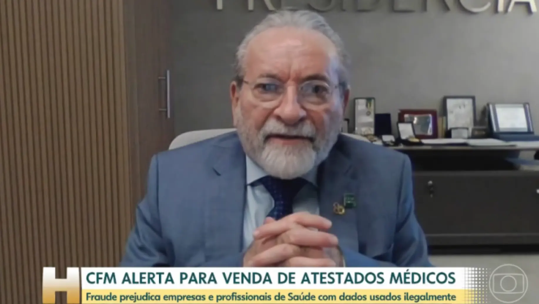 atestado: Homem idoso com barba e óculos, usando terno azul e gravata, sentado em escritório. Na imagem aparece a mensagem “CFM ALERTA PARA VENDA DE ATESTADOS MÉDICOS” e alerta sobre fraude.