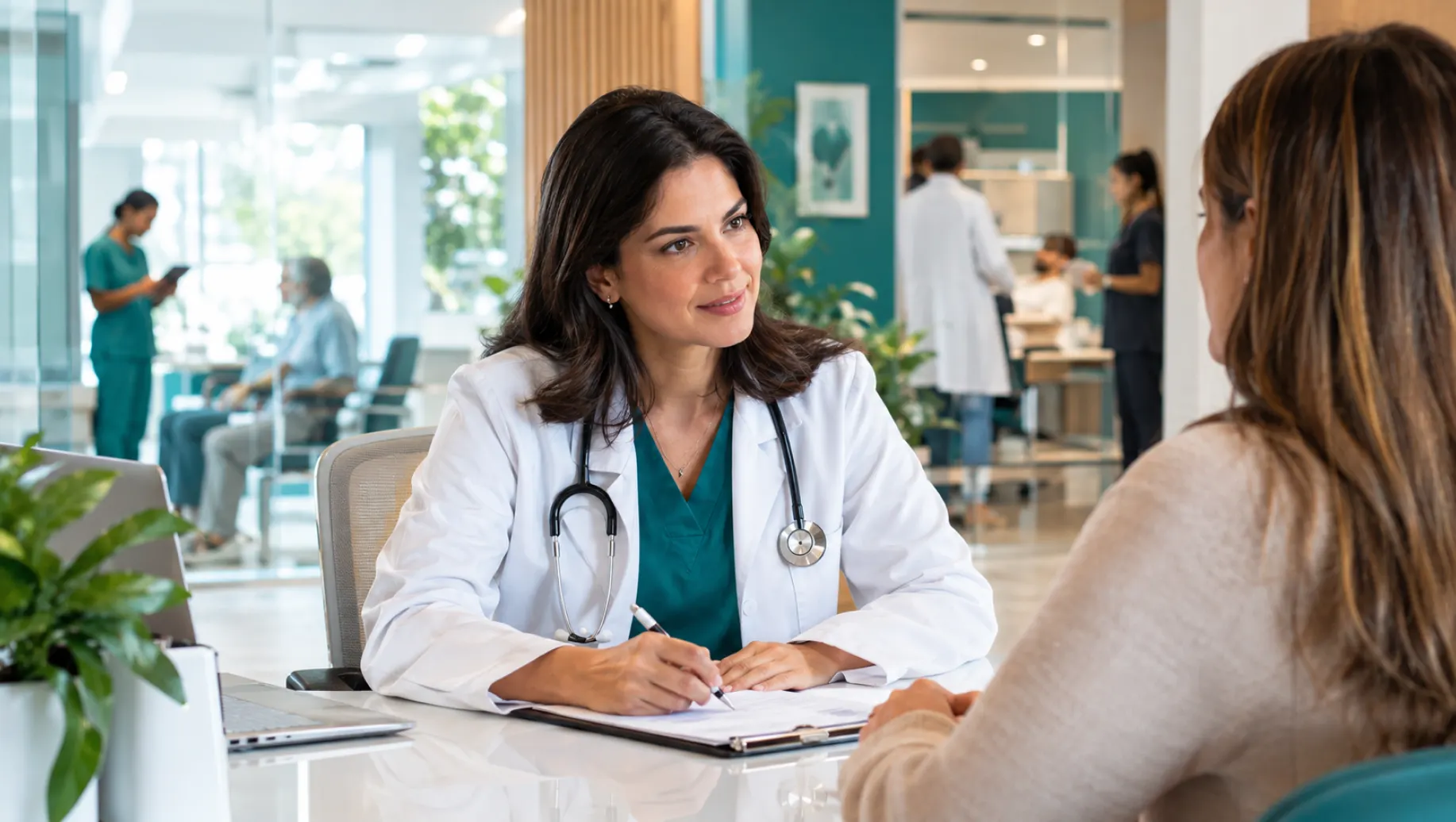 Médica em consultório, usando jaleco branco e estetoscópio, conversa com uma paciente sentada à mesa enquanto anota informações em um atendimento clínico, psicologia e psiquiatria e saúde mental